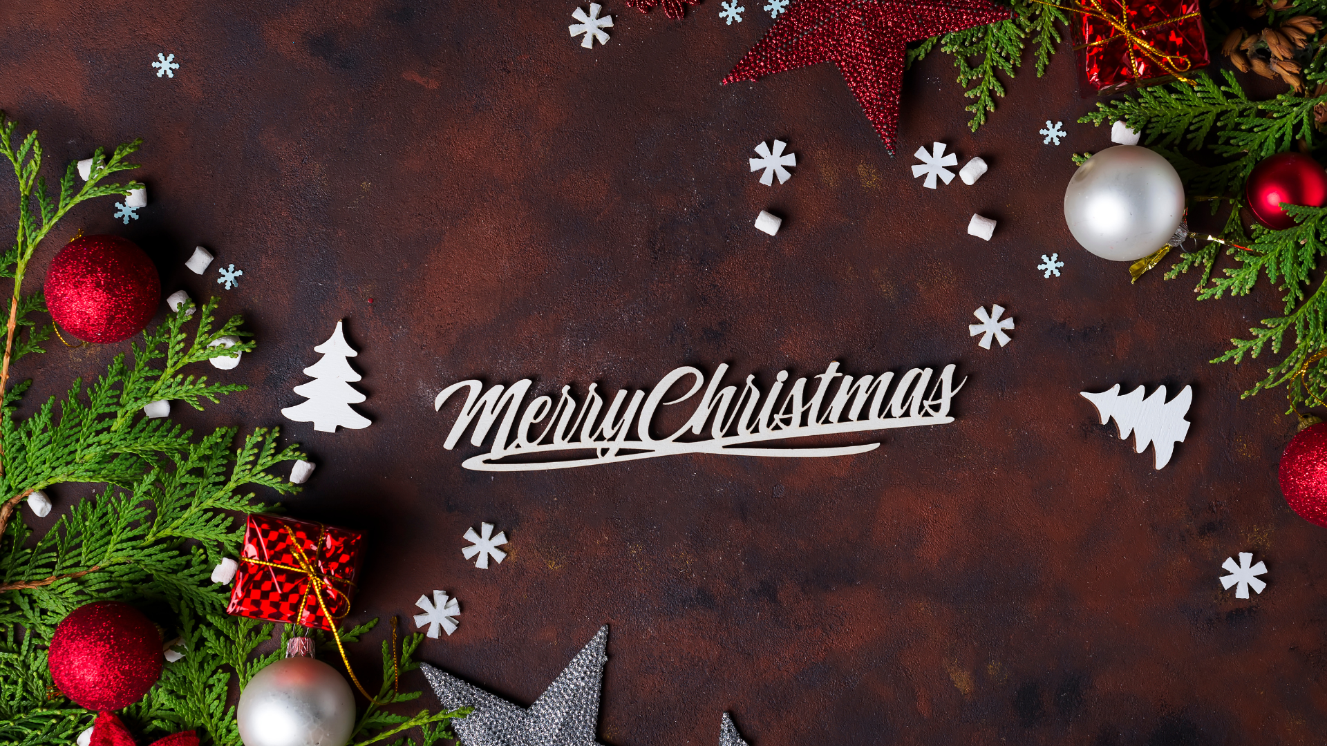 Christmas tree branches with Christmas toys, gift boxes and snowflakes on a concrete brown background, with text Merry Christmas